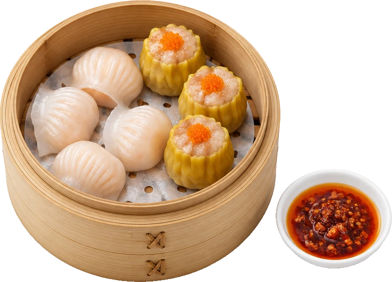 A bamboo steamer of shrimp har gow and pork siu mai beside a dish of chilli oil